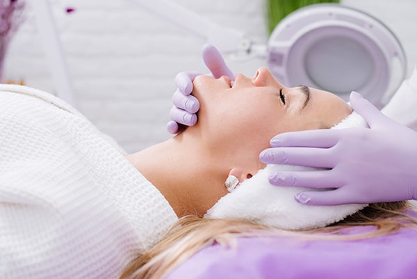 A beautician make face massage to the patient in the beauty salon