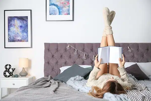 Young woman reading book on bed at home