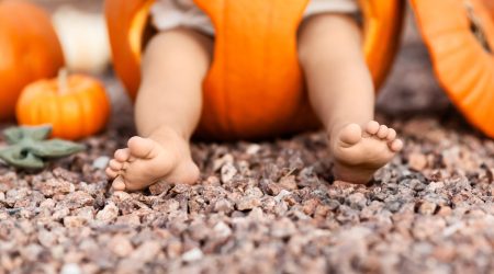 Closeup of baby legs inside orange pumpkin at Halloween, season holiday concept - Image