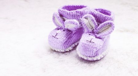 Knitted purple baby booties with rabbit muzzle over fur