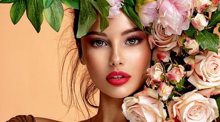 Beautiful white girl with flowers. Stunning brunette girl with big bouquet flowers of roses. Closeup face of young beautiful woman with a healthy clean skin. Pretty woman with bright makeup