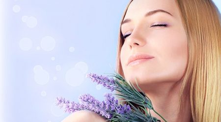 Young woman enjoying lavender flower scent, close up on clean skin female face, sensual girl at spa aromatherapy, health and beauty treatment, wellness concept