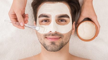 Unshaven man having cosmetic mask in spa salon, top view