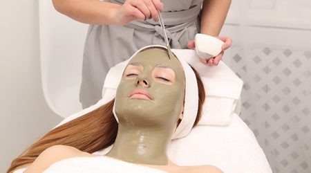 Young Woman having cosmetic facial seaweed treatment in spa.