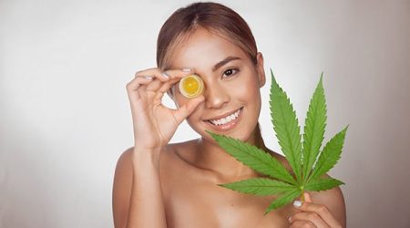 Brunette woman with CBD cream made from cannabis extract for a n